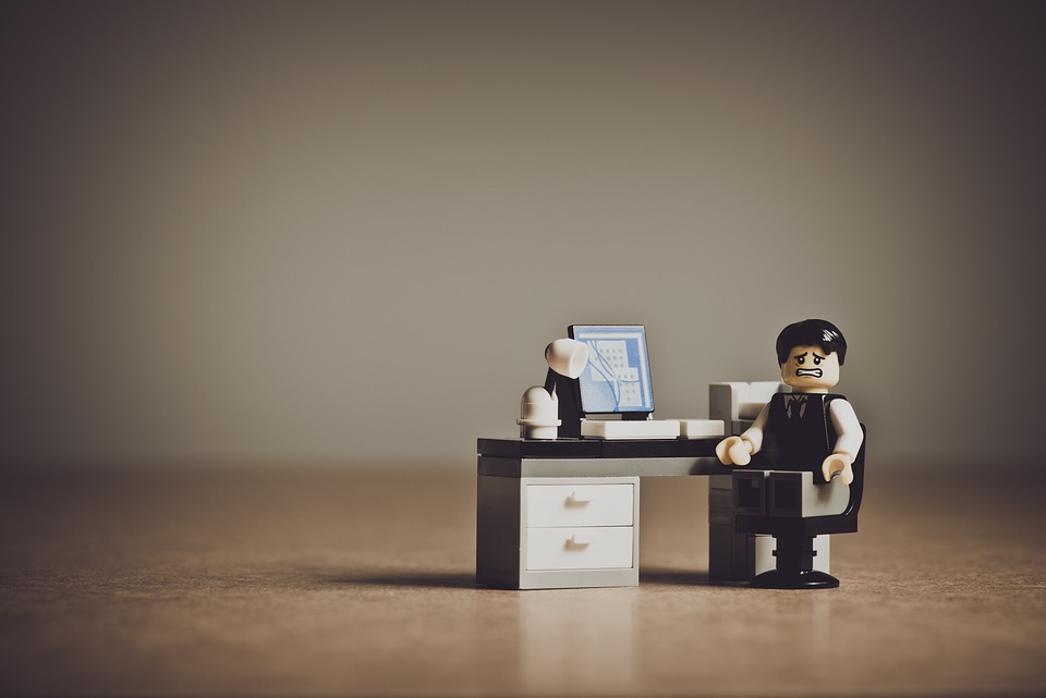 Image d'un bonhomme lego assis à son bureau qui semble désespéré devant son ordinateur