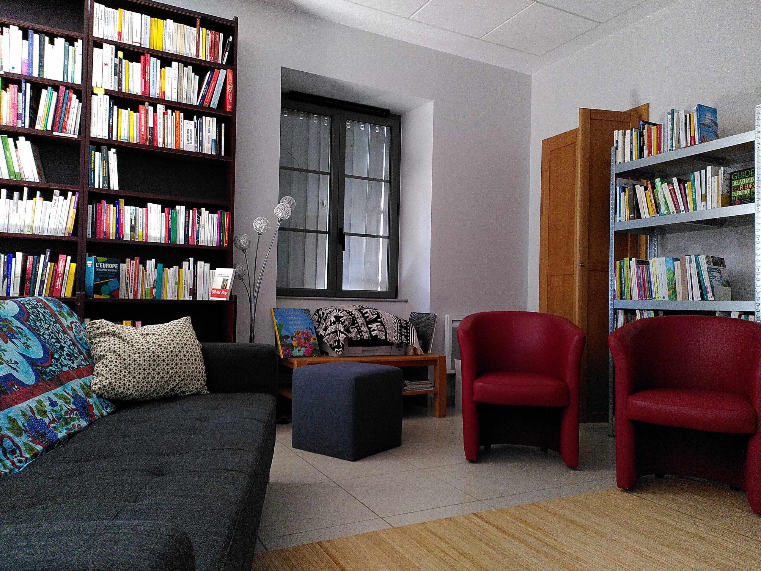 Bibliothèque du Sonneur, on voit un canapé, des fauteuils rouges et des étagères pleines de livres