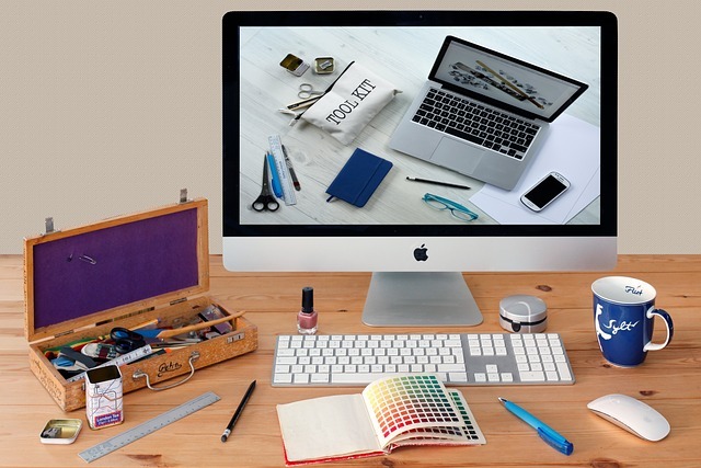 Image représentant un ordinateur mac, clavier, souris, une palette de couleur, une tasse de café, un crayon, un règle, une boite en bois
