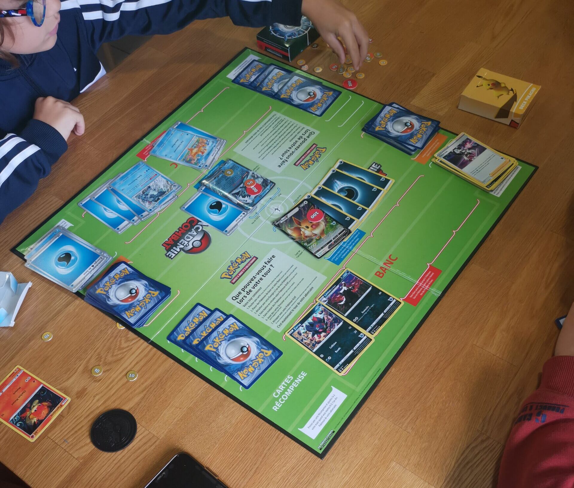 Une partie de Pokémon JCC se déroule avec un plateau de jeu et des cartes